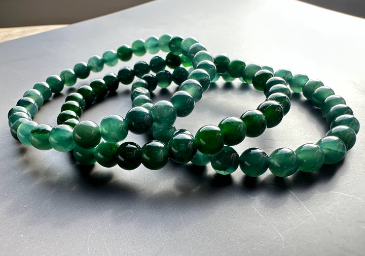 Guatemalan jadeite bead bracelet with 6mm round green beads coiled on a dark surface