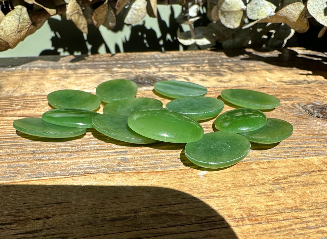 Group of Canadian nephrite jade oval cabochons 18x25mm on a rustic wooden surface.