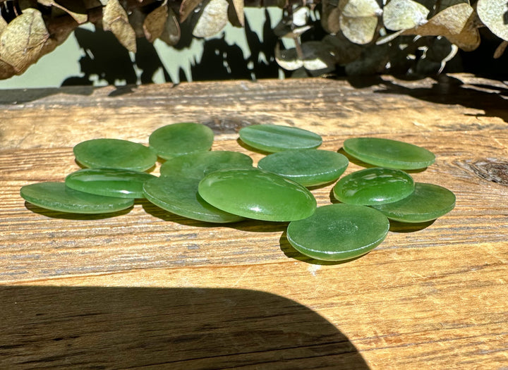 Group of Canadian nephrite jade oval cabochons 18x25mm on a rustic wooden surface.