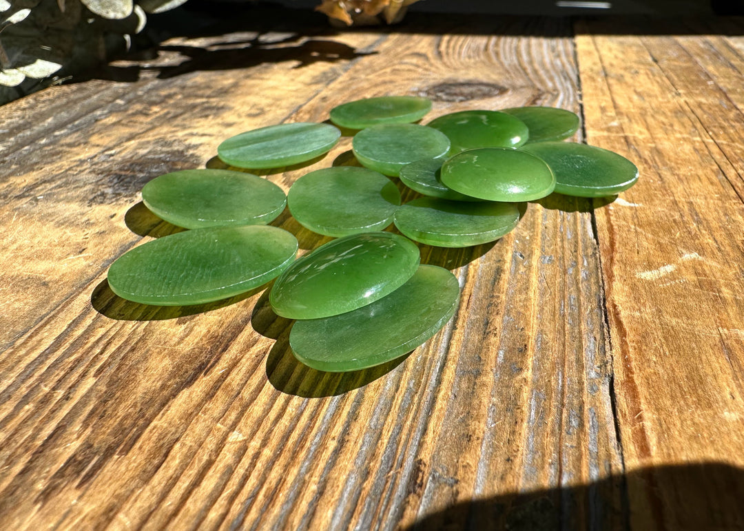 Canadian nephrite jade oval cabochons 18x25mm on a rustic wooden surface