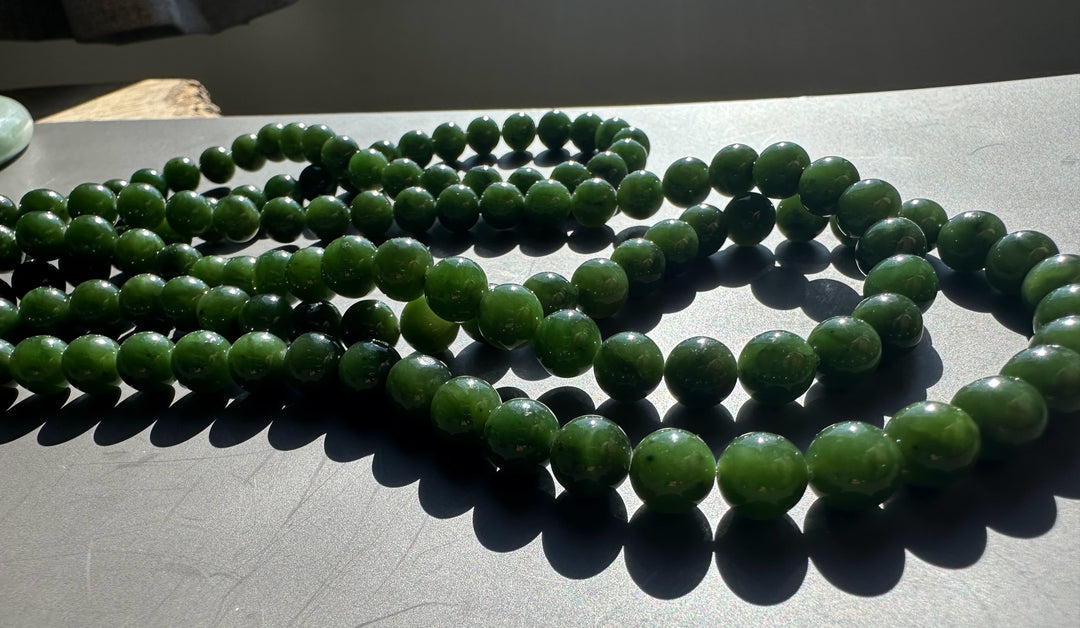 8mm dark green Canadian unstrung beads on multiple strands spread across a gray surface