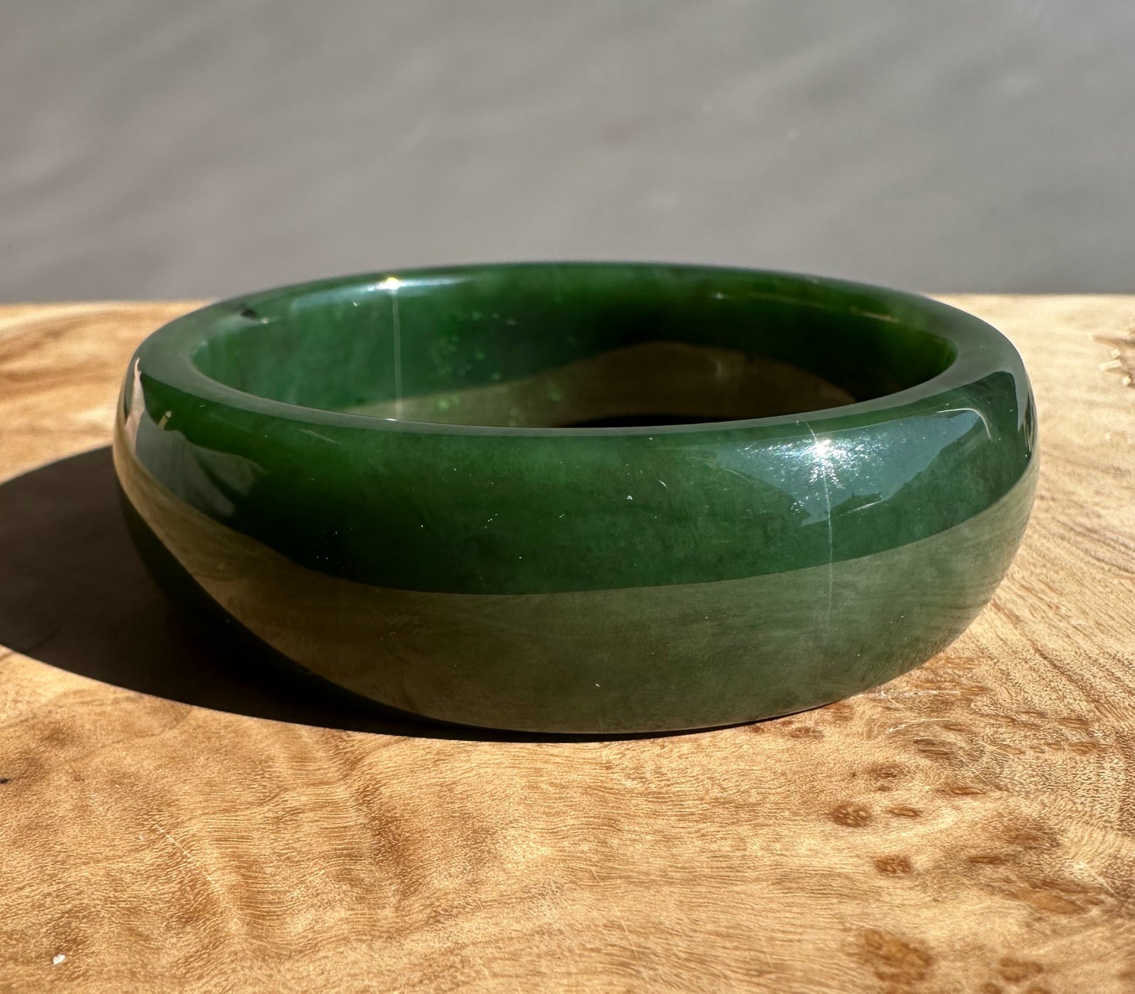 Side view of Canadian Jade Bangle showing layered dark and light green bands and a polished surface.