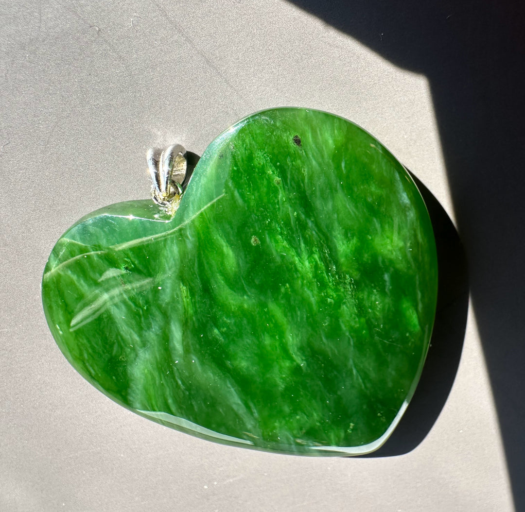 A+ Polar Jade large green heart pendant with a silver bail on a gray surface