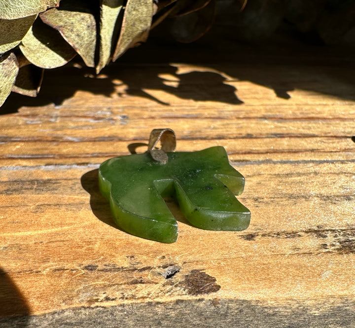 Bright green jade Chai pendant on a dark cord with a metal bail
