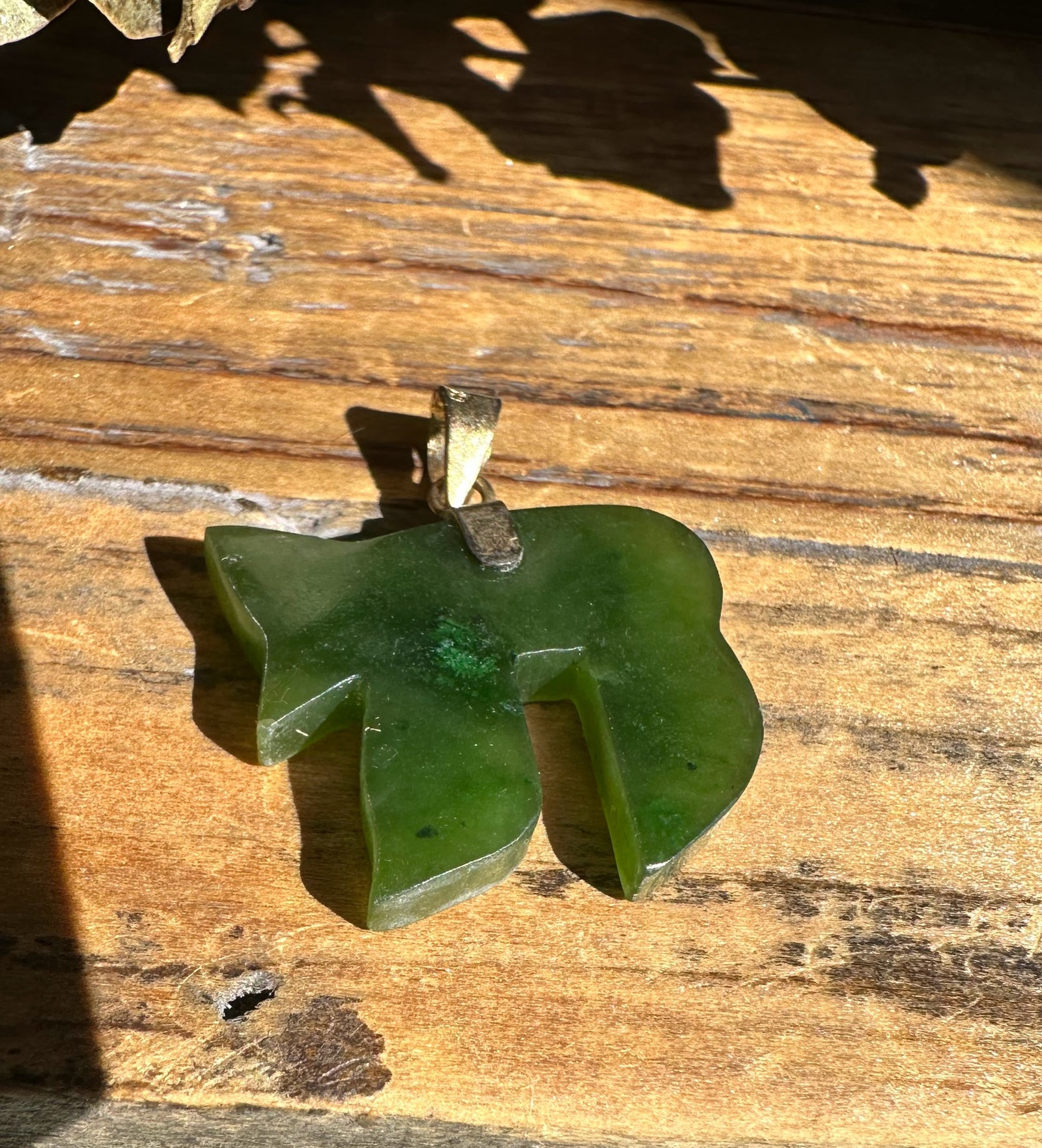 Vintage 20mm green jade Chai pendant with brass bail on wood surface