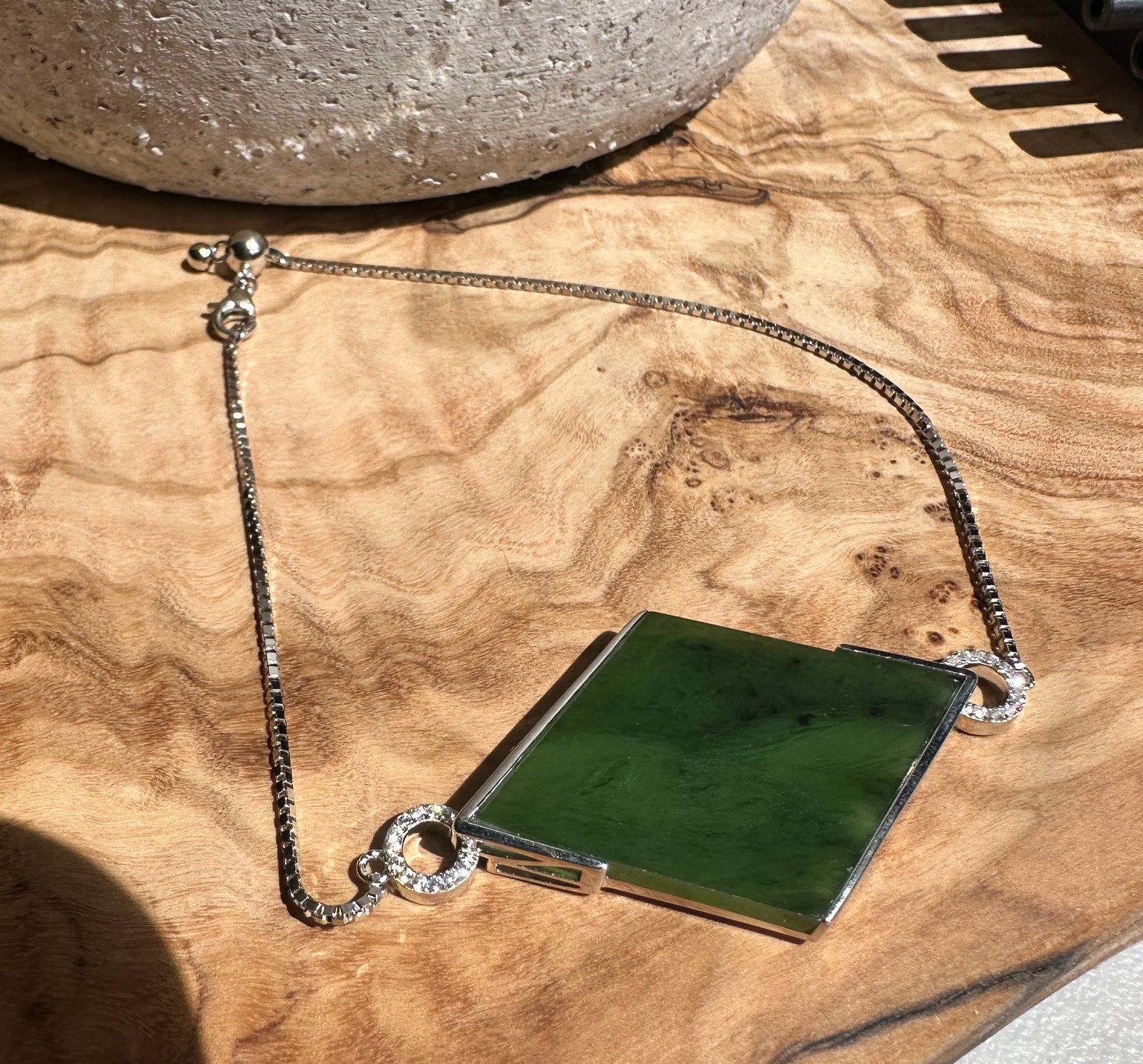 Sterling silver bracelet with a rectangular green Canadian jade centerpiece and diamond studded circular connectors