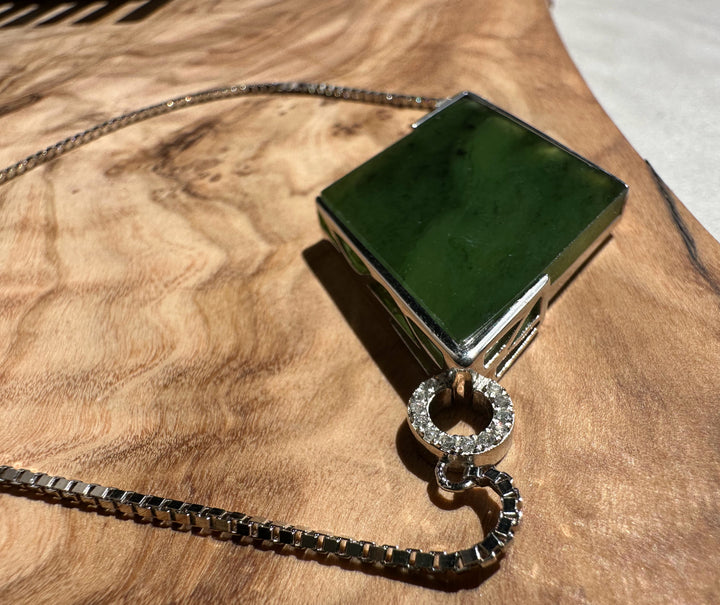 Close-up of green rectangular jade pendant on a sterling silver bracelet with diamond accented connectors