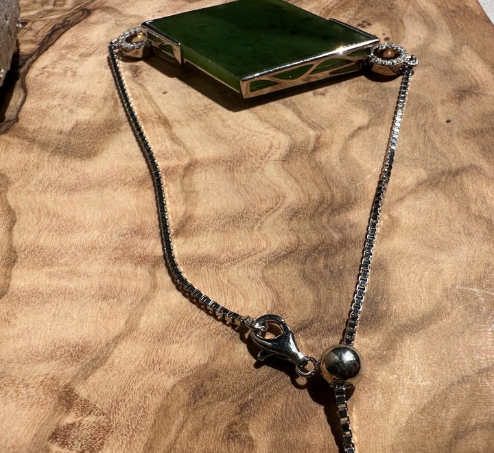 Close up of the bracelet showing a green rectangular Canadian Jade piece and diamond accented loops on each end