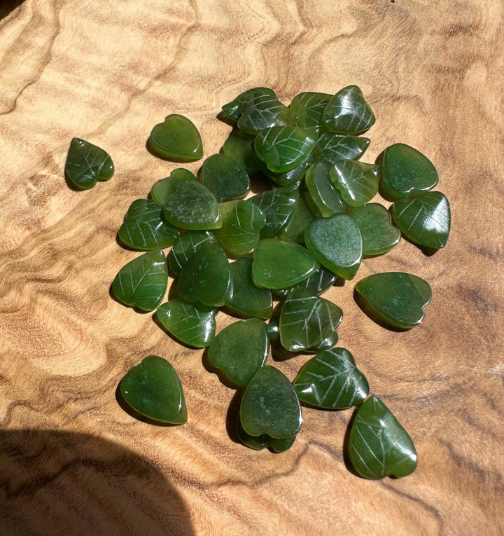 Group of green jade leaf shaped beads 9x8mm on a wooden surface.