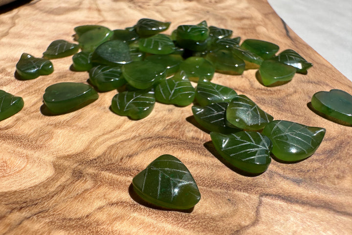 Canadian Jade Leaf beads 9x8mm spread on a wooden surface showing vein markings