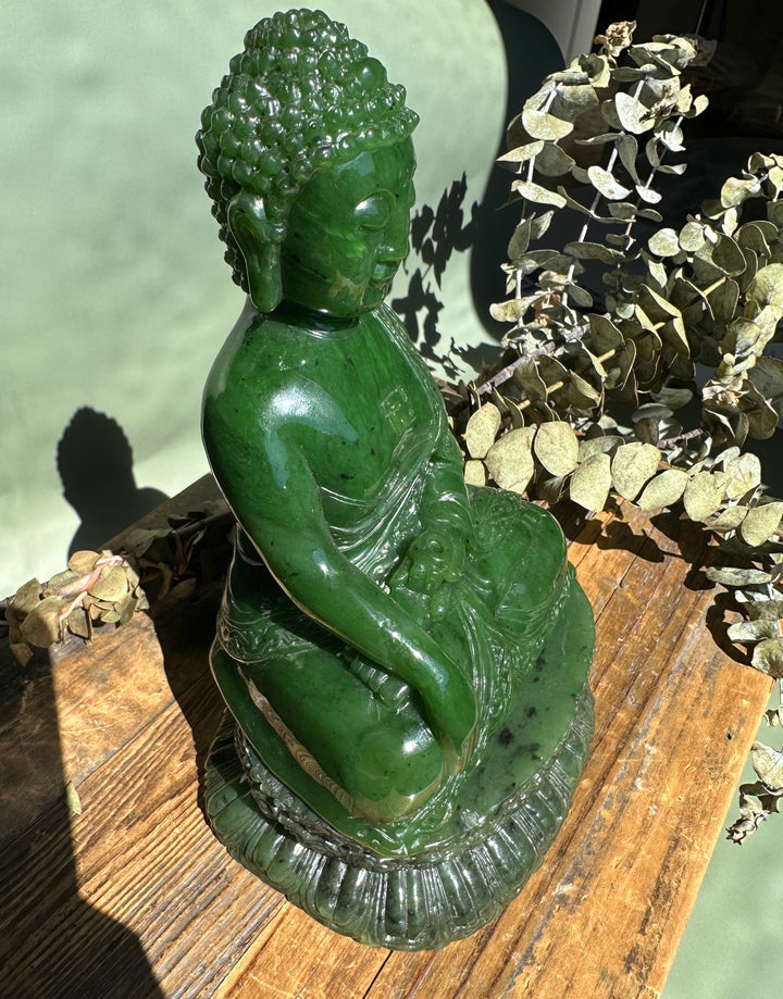 Green nephrite jade Shakyamuni Buddha viewed from the side, seated in meditation on a carved base