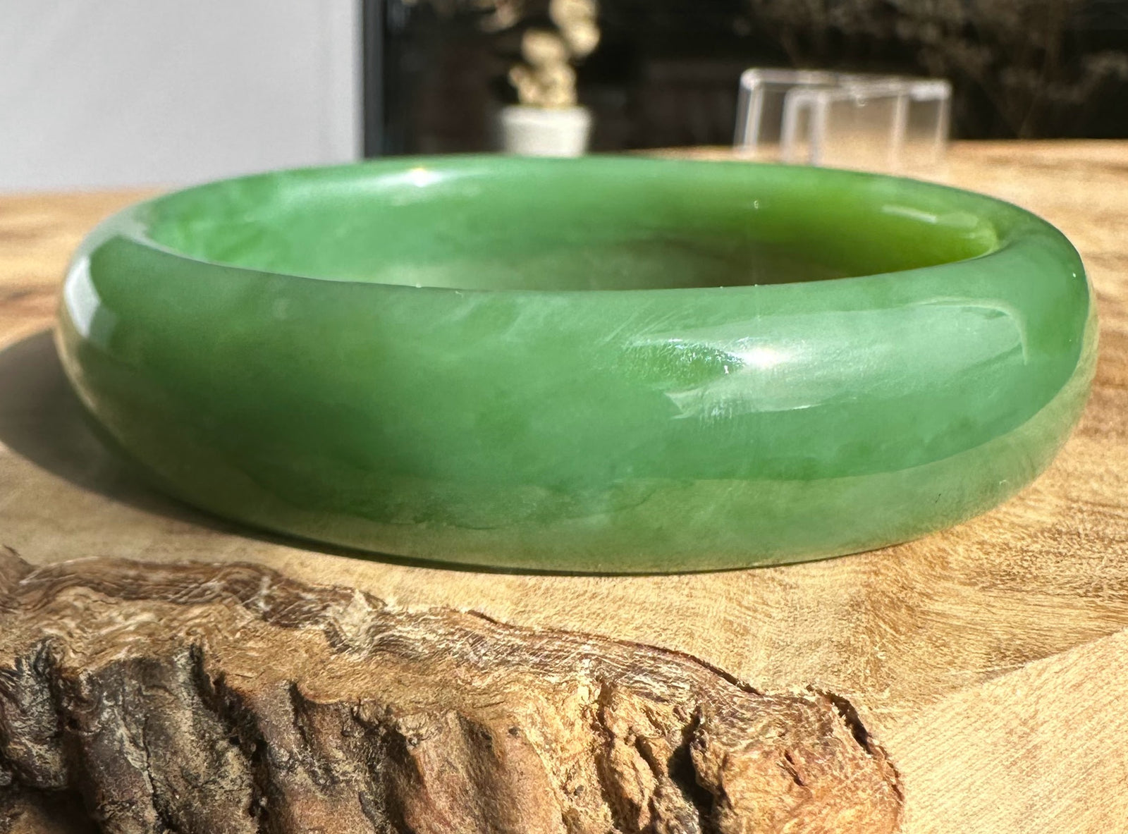 Siberian Bangle in green jade viewed from the side showing a rounded interior edge on a wood surface