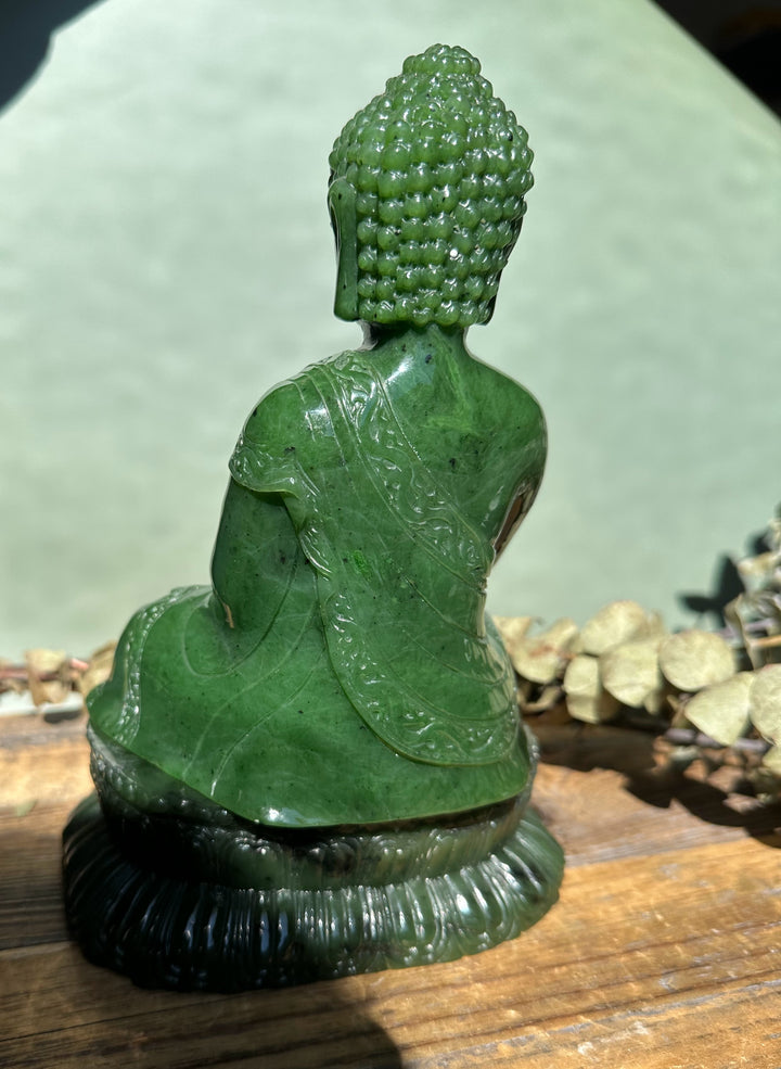 Back view of Shakyamuni Buddha carved from Canadian nephrite jade, seated with detailed robe on a carved pedestal.
