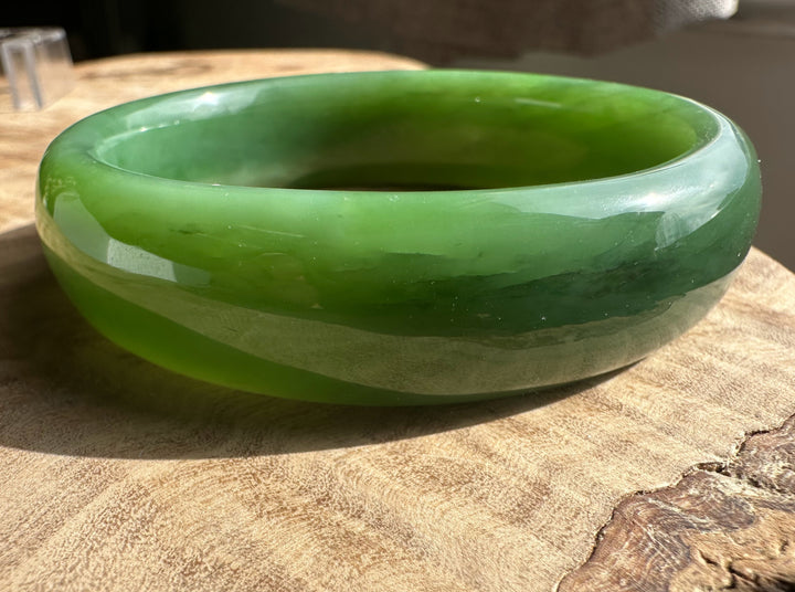 Siberian jade bangle worn on a wrist showing layered green tones.