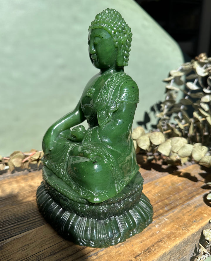 Side view of emerald green nephrite Shakyamuni Buddha seated with draped robe and lotus pedestal