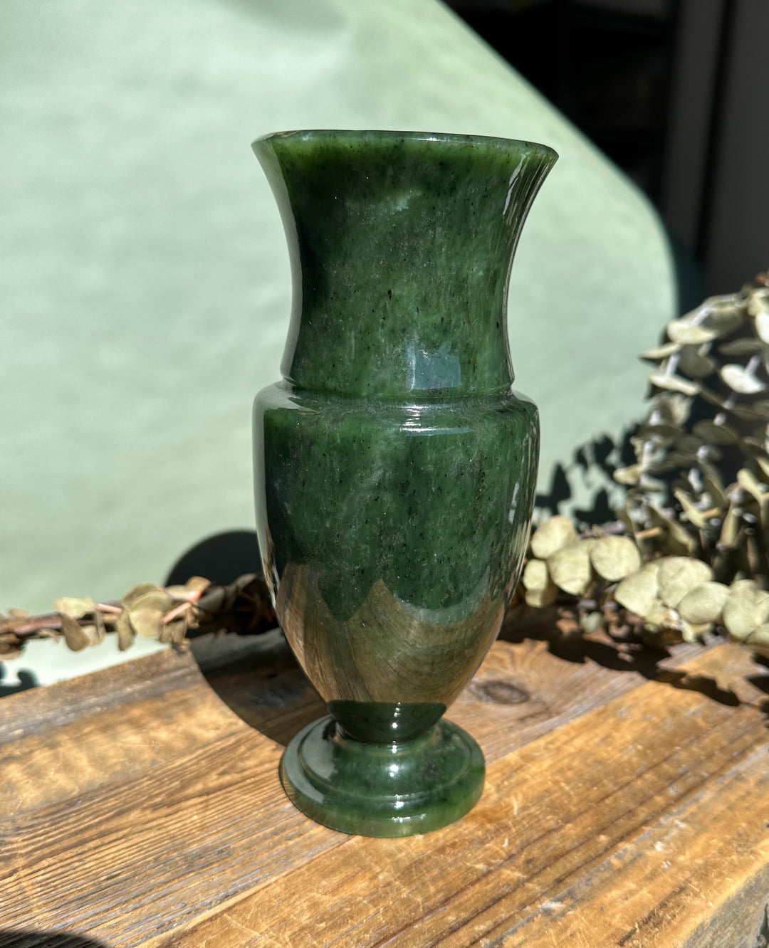 Siberian Jade Vase with tall slender neck and flared top in dark green marble, placed on a wooden table.