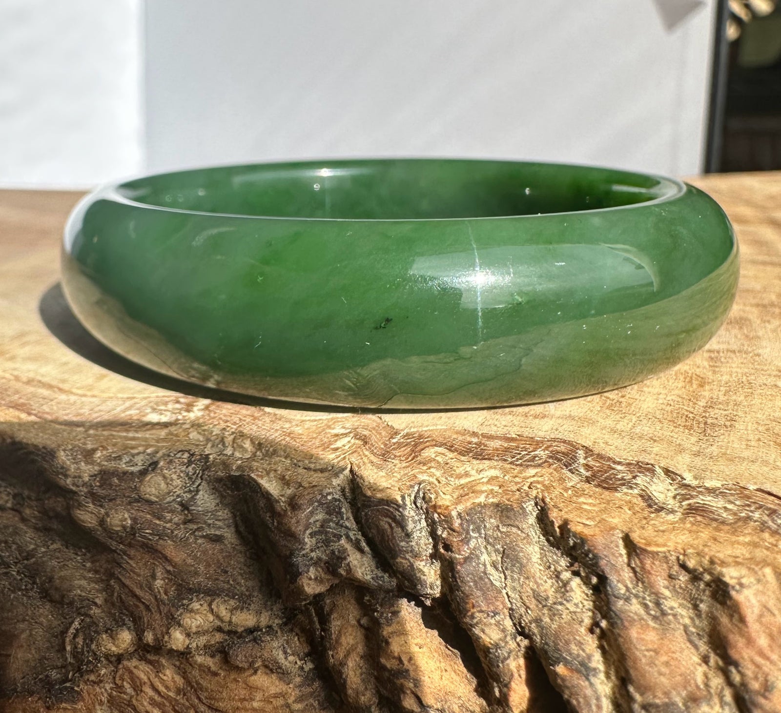 Canadian Jade Bangle 54.5 x 15mm in polished green jade resting on a rustic wood surface