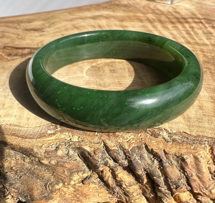 Canadian Jade Bangle 54.5 x 15mm angled to show the rounded inner opening on a wooden surface