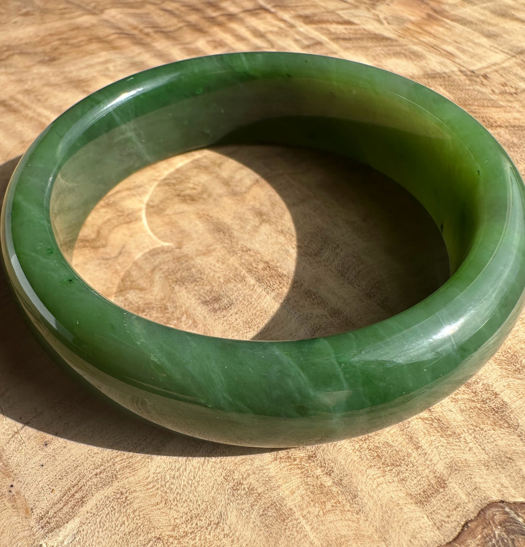 Top view of a jade bangle showing a lighter outer edge and darker interior