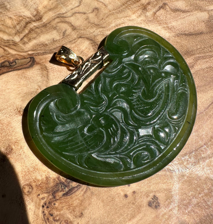 Vintage jade birds pendant in dark green with swirling carved pattern and a gold bail