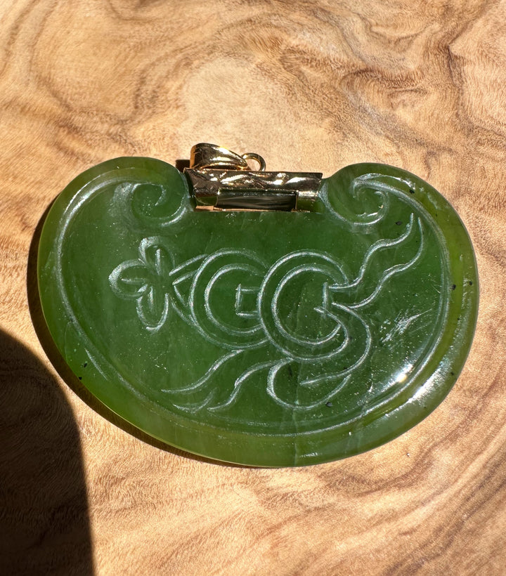 Dark green jade pendant with a carved birds motif and a metal bail