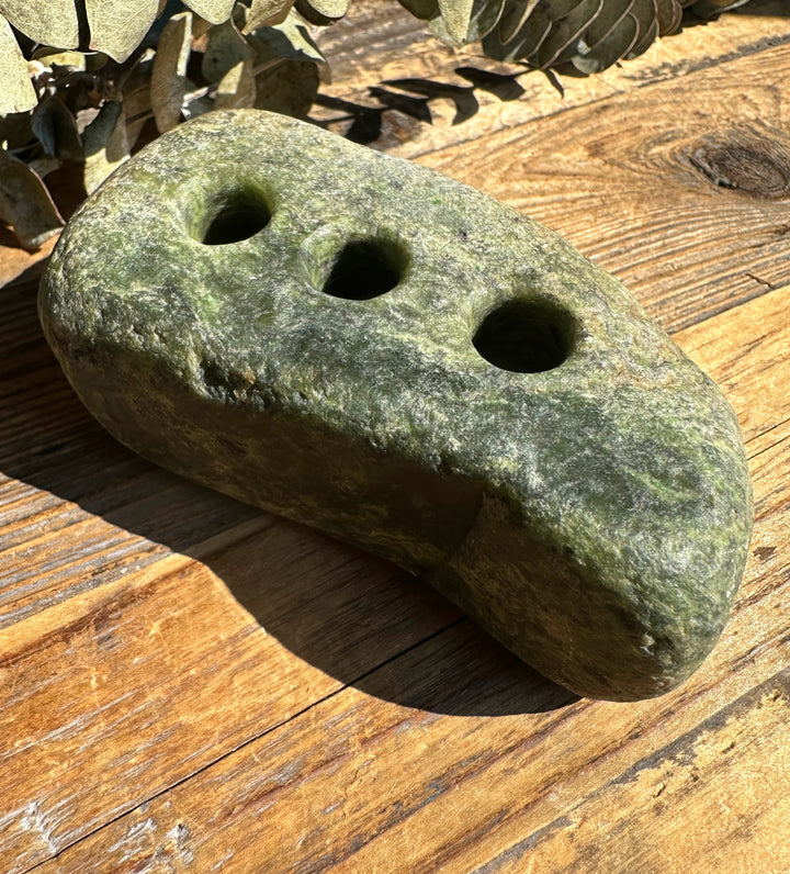 Close up of rough jade pen holder showing three top holes on a green mottled stone.