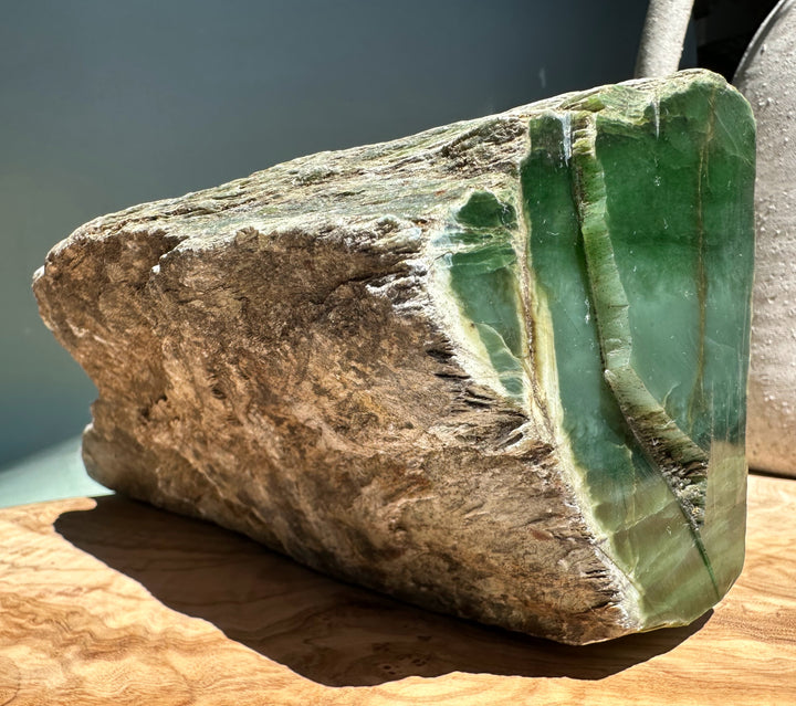 Rough Siberian nephrite block with green jade core exposed on the cut edge and weathered exterior.