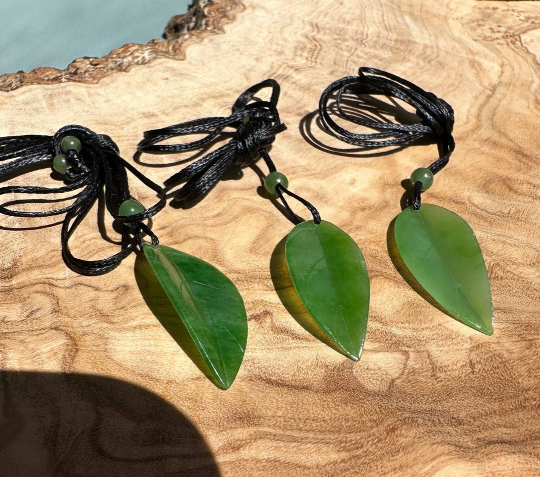 Three green leaf pendants on black braided cords with round green beads