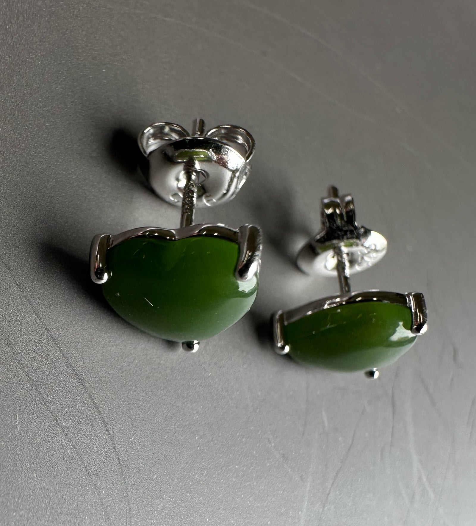 Close up of silver and jade heart earrings showing glossy green jade hearts.