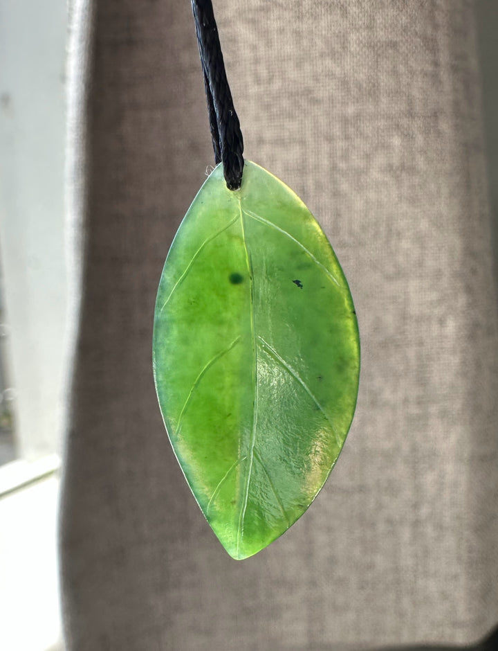 Green leaf pendant with visible veins hanging from a black cord
