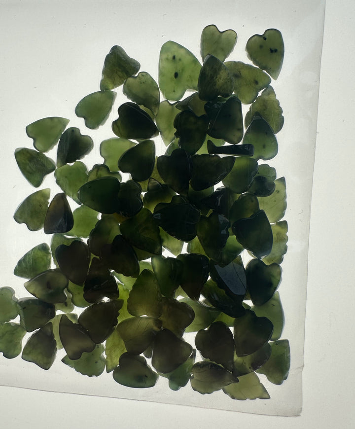 Translucent green jade leaf shapes scattered on a white surface
