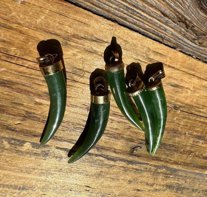 Jade horn pendants with brass caps spread across a wooden surface