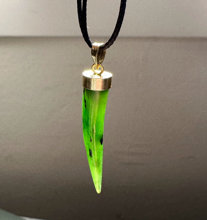 Talon shaped jade pendant in neon green with a silver cap on a black cord necklace