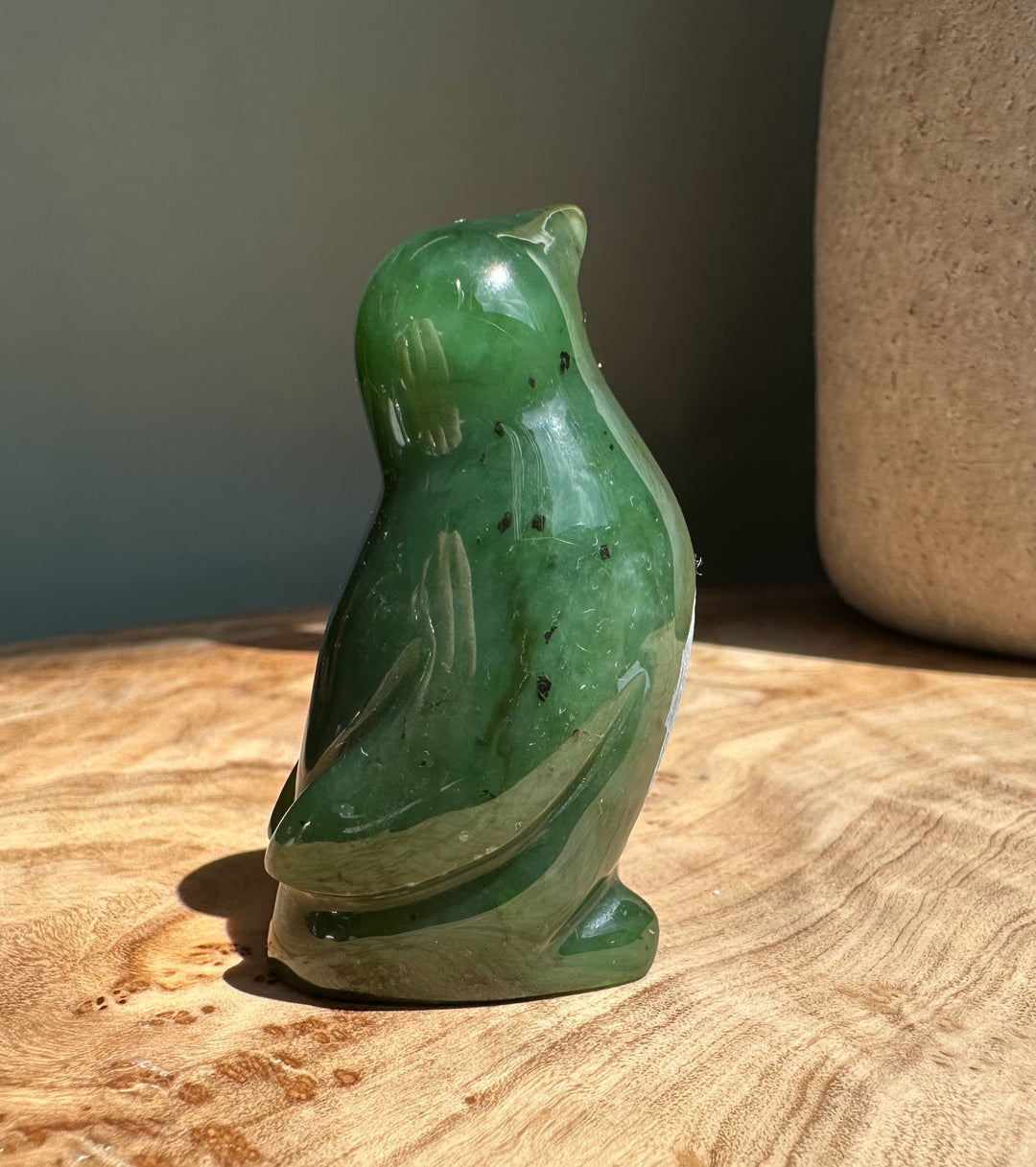 2-inch nephrite jade penguin figurine on a wooden surface.