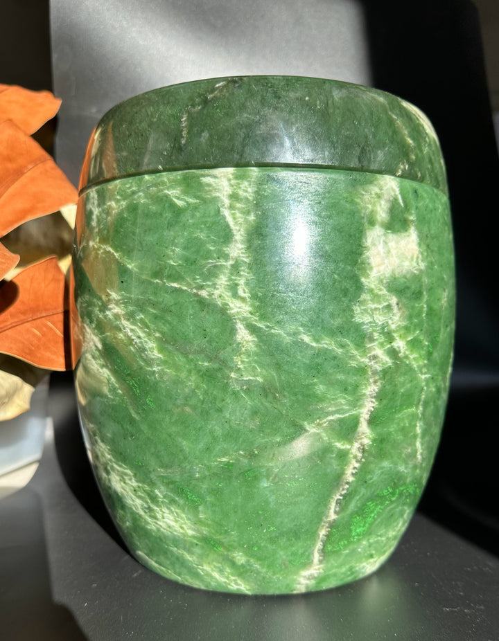 Close up angle of green jade burial urn with lid in place highlighting marbled white veins