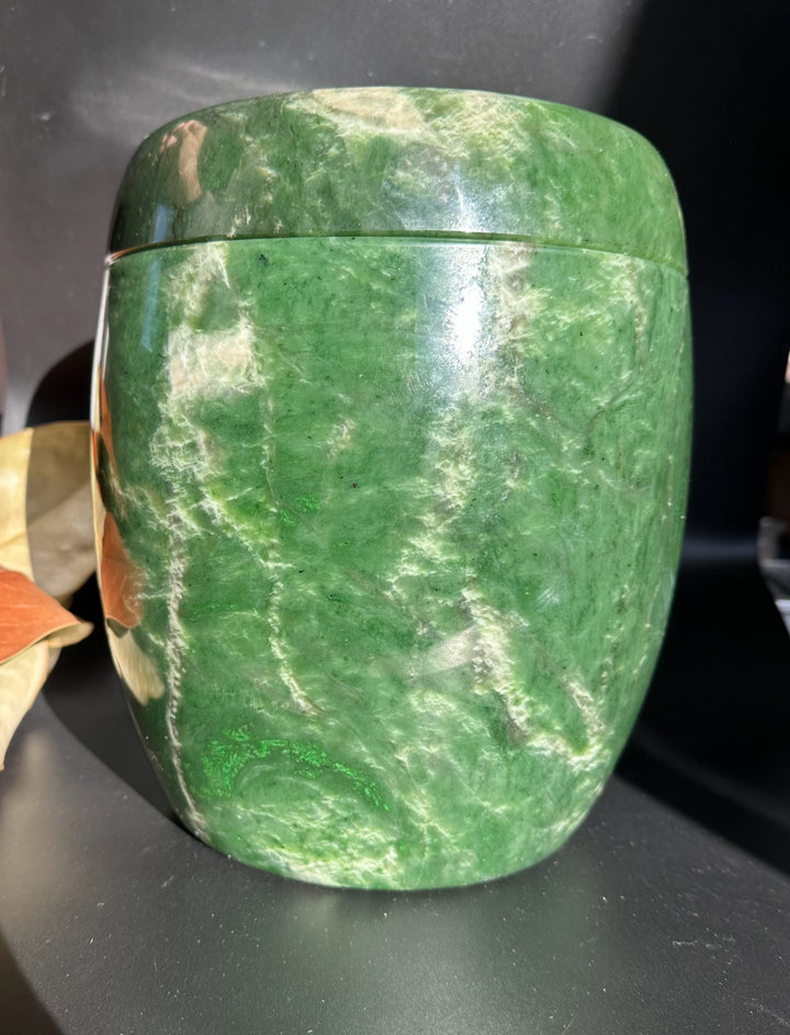 Green jade burial urn with lid on, showcasing smooth polished stone and natural veining