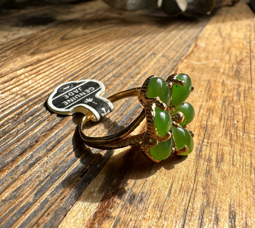Vintage Jade Ring featuring a flower cluster of green jade beads in a gold setting on a wooden surface.