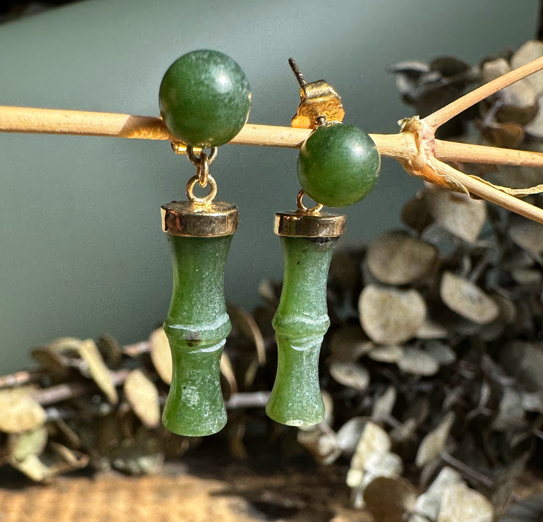 Detail of green jade top beads and bamboo drop pendants with gold caps on a natural backdrop