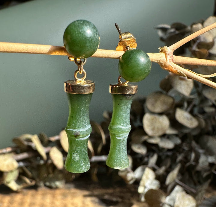 Detail of green jade top beads and bamboo drop pendants with gold caps on a natural backdrop