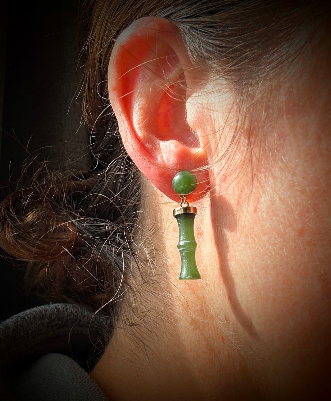 Green jade bead earring with bamboo pendant worn on the ear