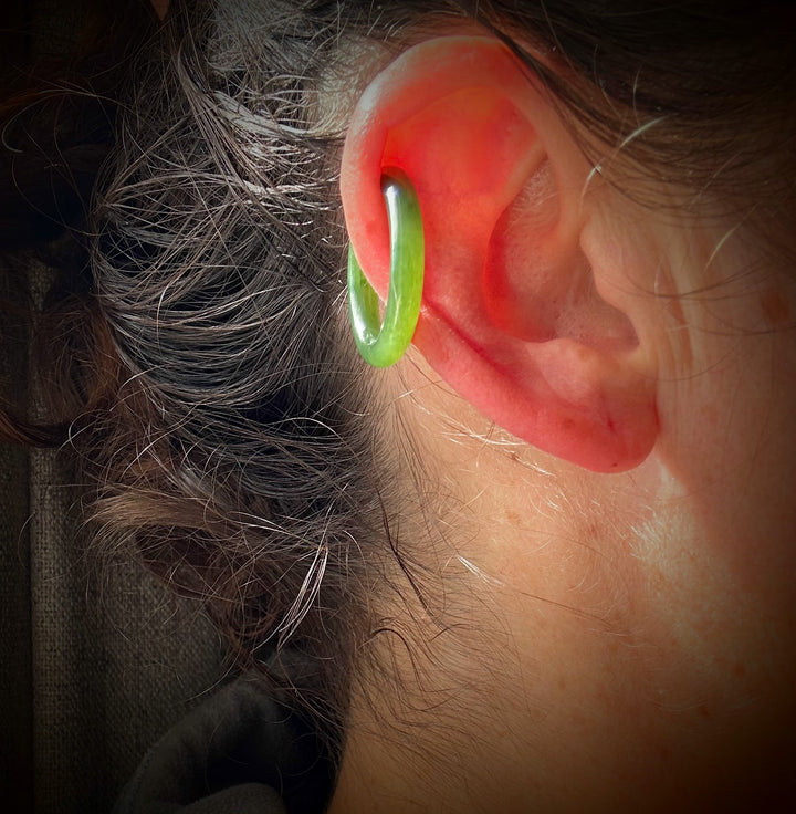 Green jade ear cuff worn on the ear in profile view