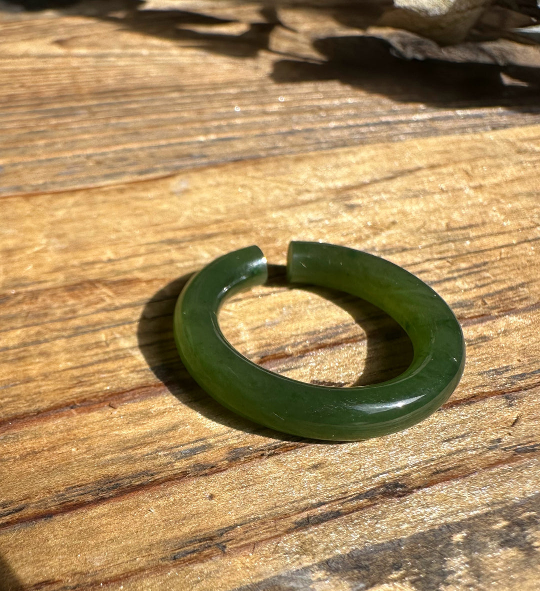 Green jade ear cuff 25mm circular hoop on warm wooden surface