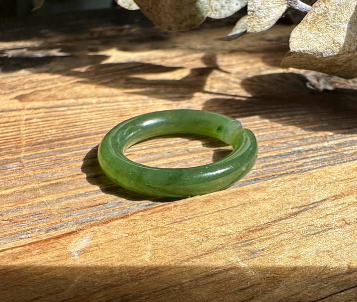 Green jade ear cuff 25mm circular hoop on wood surface in bright sunlight