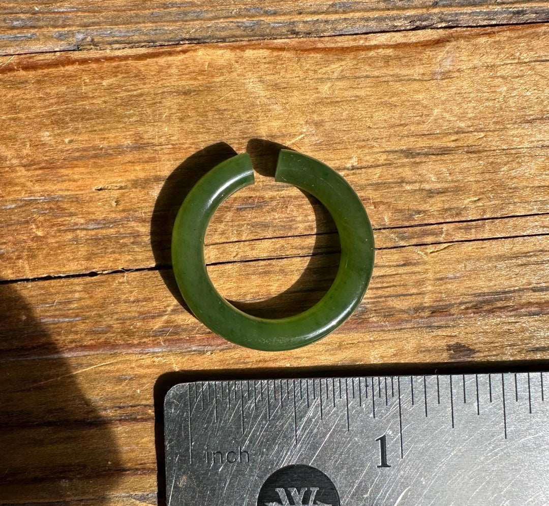 Green jade ear cuff 25mm circular hoop beside an inch ruler on wood surface