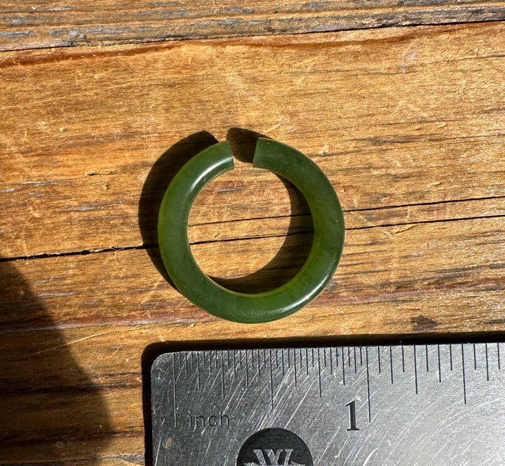 Green jade ear cuff 25mm circular hoop beside an inch ruler on wood surface