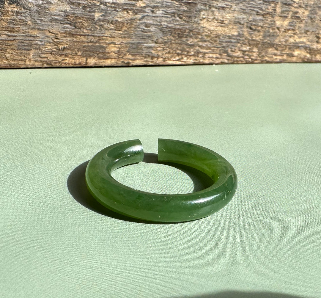Jade ear cuff 25mm circular ring with an opening resting on a green textured surface