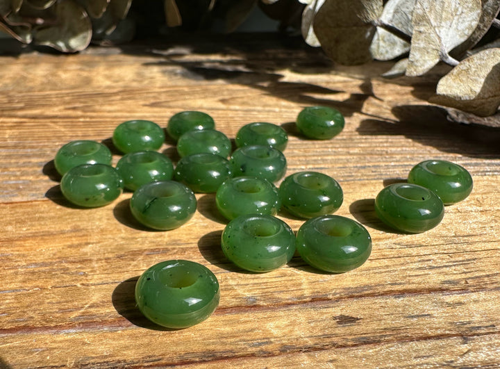 Green donut shaped beads scattered on a sunlit wooden surface