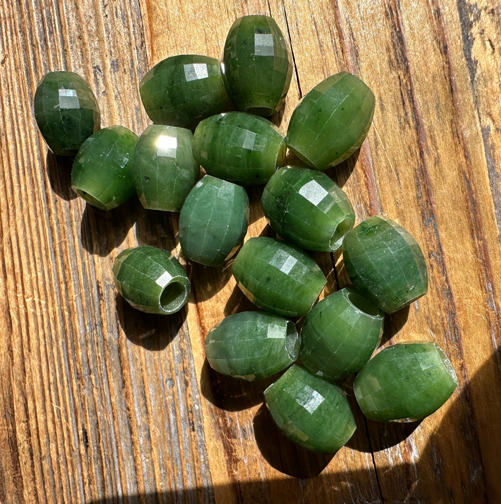 Cluster of faceted Canadian Jade beads 14x12mm with drilled holes on wood