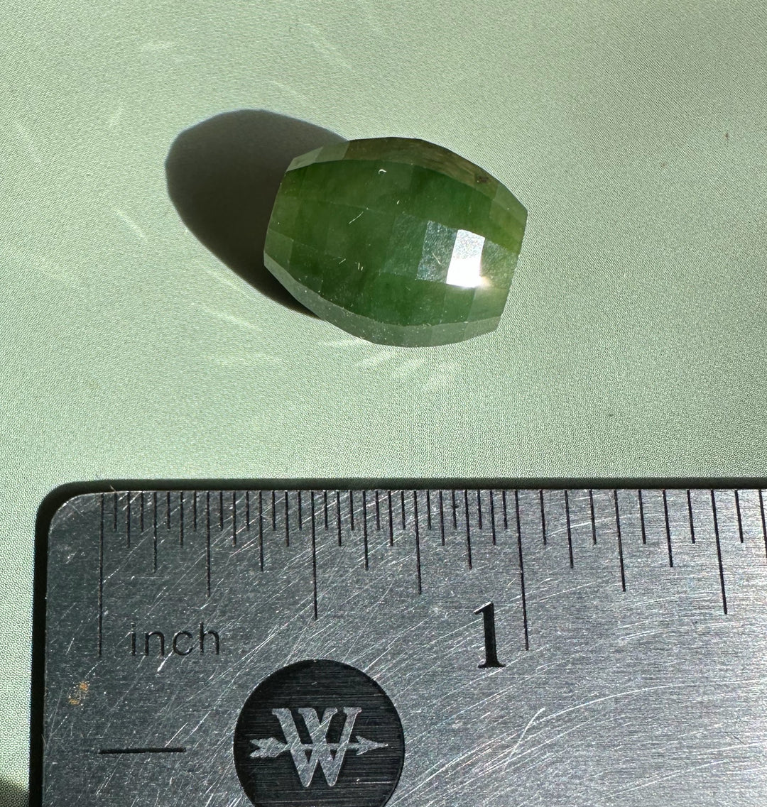 Single faceted Canadian Jade bead 14x12mm beside a ruler for scale