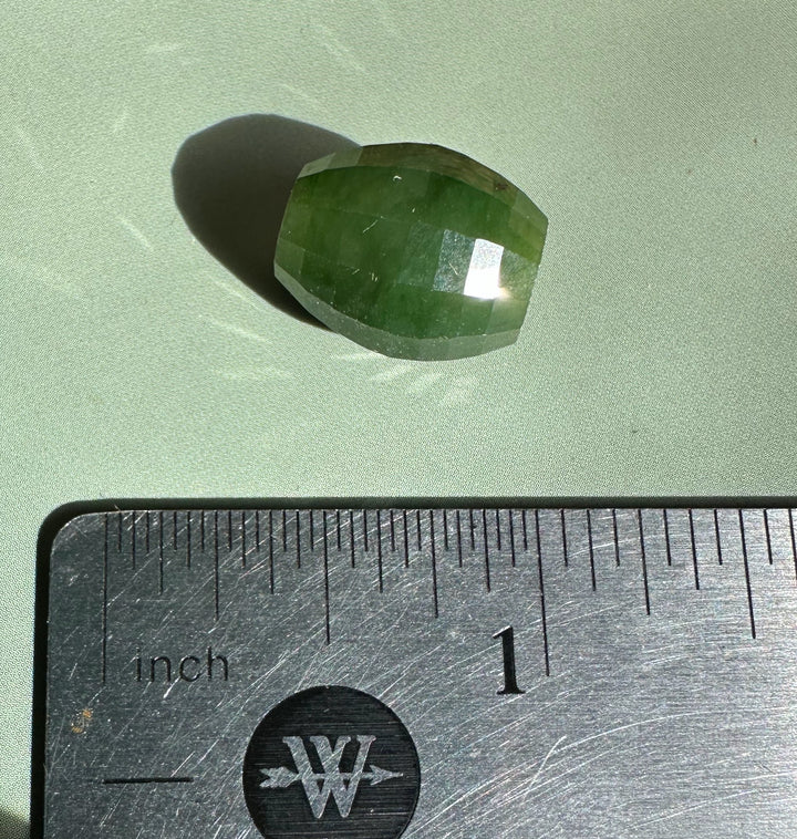 Single faceted Canadian Jade bead 14x12mm beside a ruler for scale